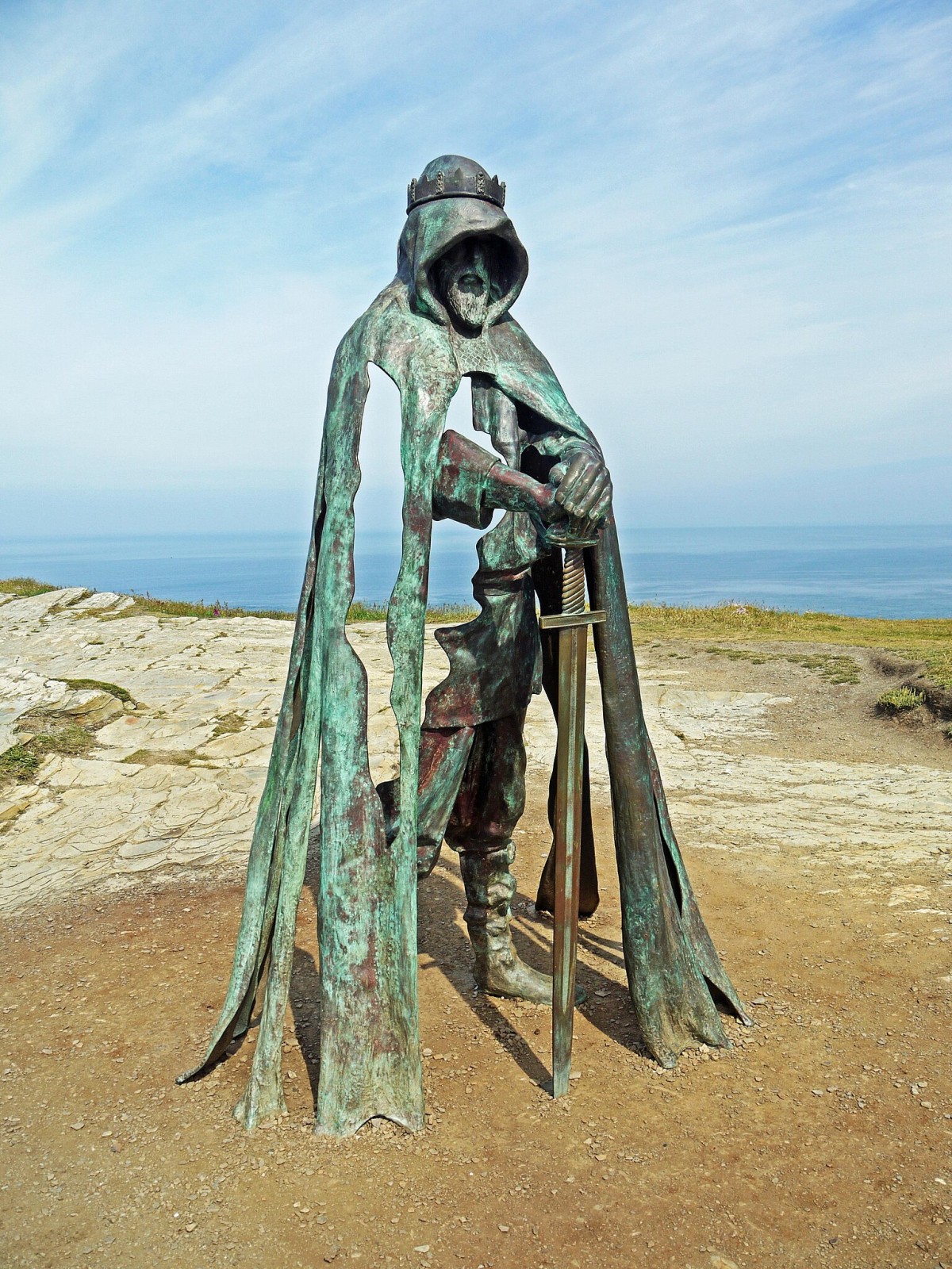 En lo alto de los acantilados se encuentra una estatua de bronce del rey Arturo con su espada y mirando hacia las ruinas de Tintagel.