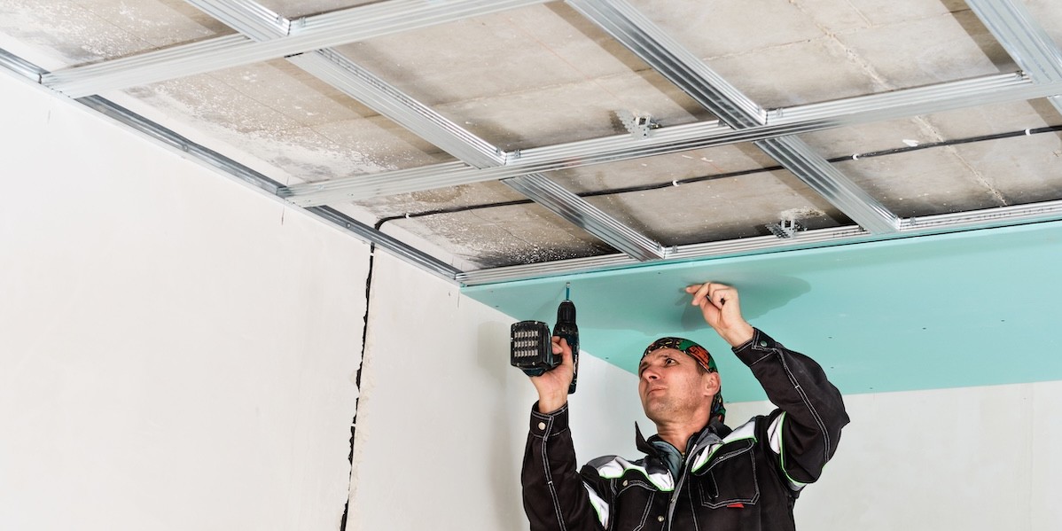 Isolamento acustico in condominio: come realizzarlo contro i rumori Operaio specializzato lavora all’insonorizzazione del soffitto
