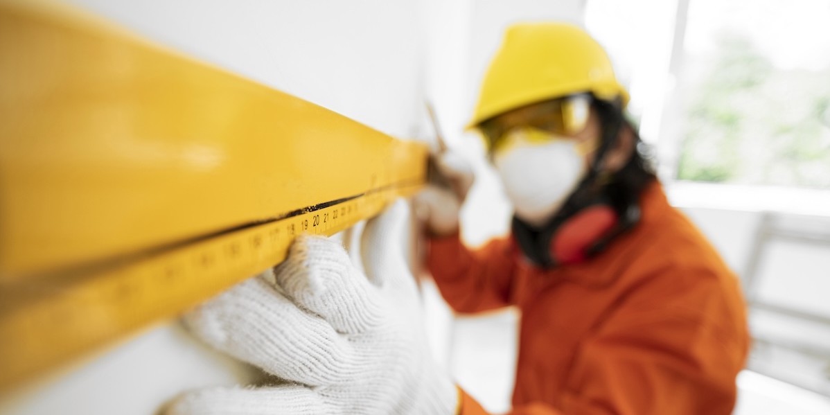 Isolamento acustico in condominio: come realizzarlo contro i rumori Operaio prende misure per installare pannelli di isolamento acustico