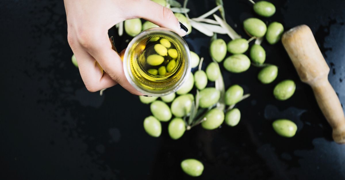 persona che sorregge un bicchiere con l'olio