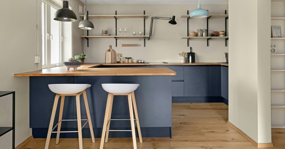 Una cucina celeste polvere con piano laboro bianco e dettagli in legno chiaro