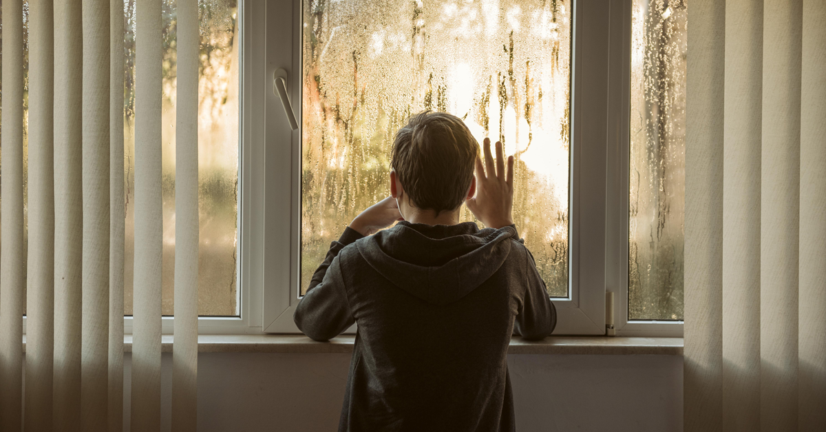 un ragazzo guarda fuori dalla finestra