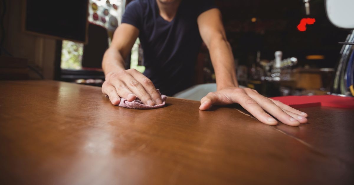 persona che pulisce ripiano in legno