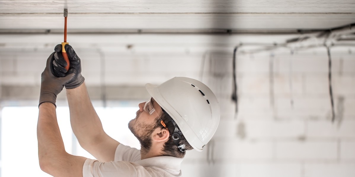 Elettricista installatore con attrezzo lavora alla configurazione dei cavi