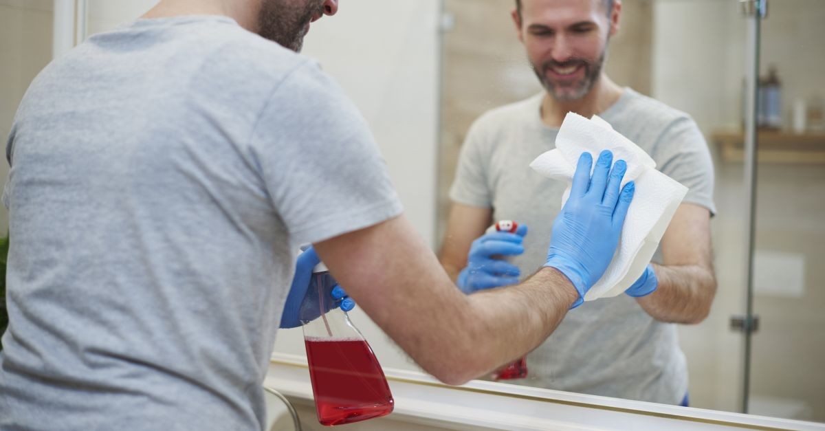 uomo che pulisce specchio