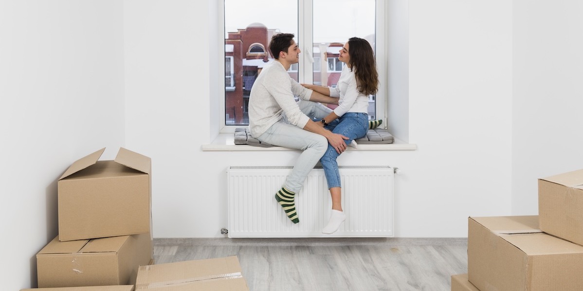Giovane coppia seduta sul davanzale della finestra che si gode il nuovo appartamento