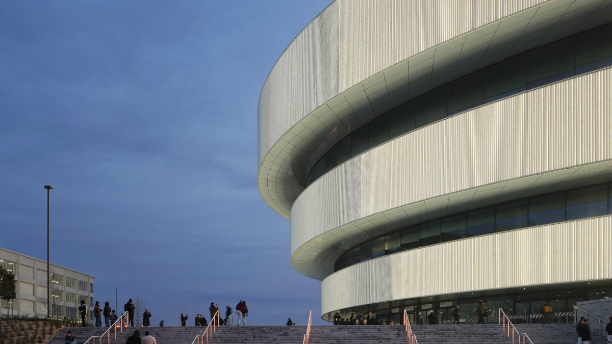 La forma elíptica del edificio se inspira en el arquetipo del anfiteatro, reinterpretado con tectónica y materiales modernos.