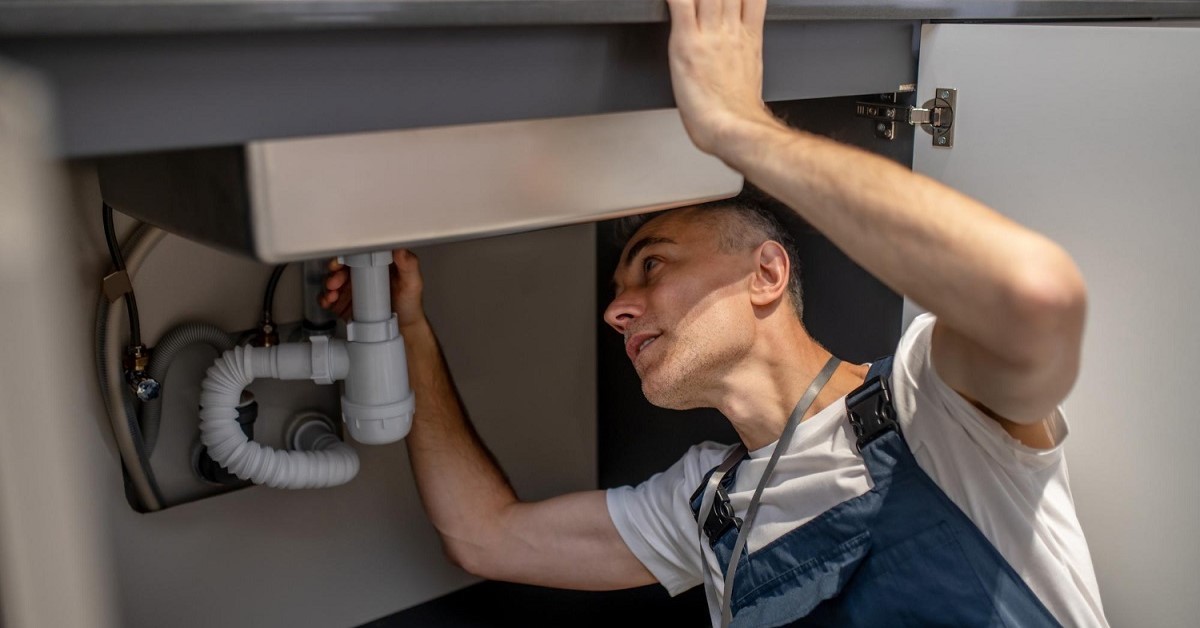 Un idraulico ispeziona lo scarico della cucina