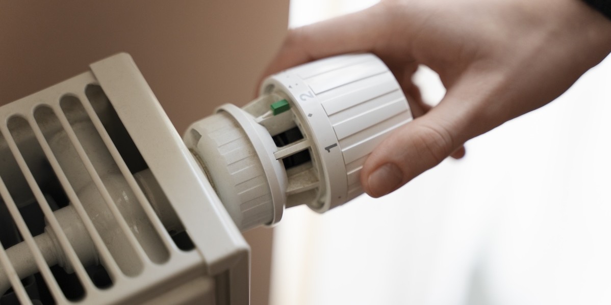 Primo piano di una mano che gira la manopola del riscaldamento