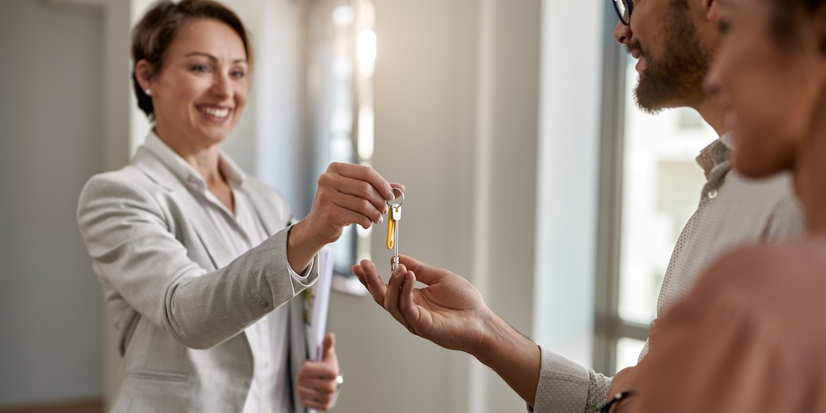 Agente immobiliare che consegna le chiavi della nuova casa a una coppia