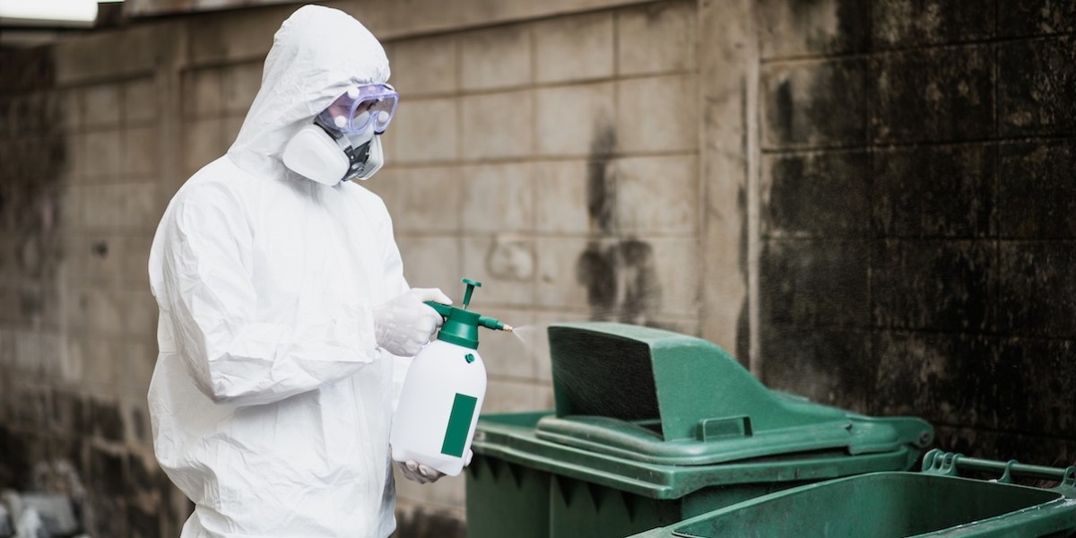 Operatore in tuta bianca di protezione chimica che disinfetta uno vano tecnico