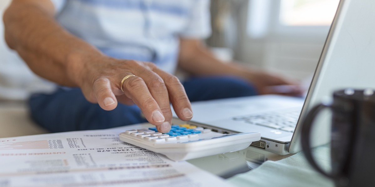 Persona anziana usa la calcolatrice e calcola le bollette