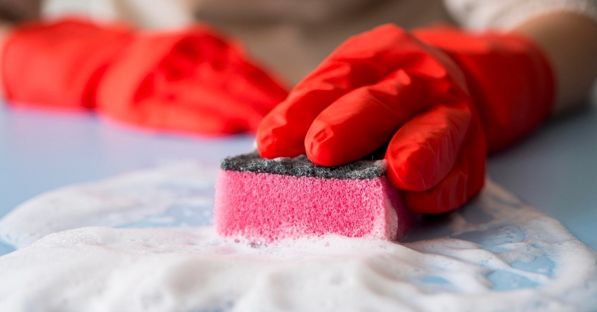 Pulizia di una superficie con una spugna rosa