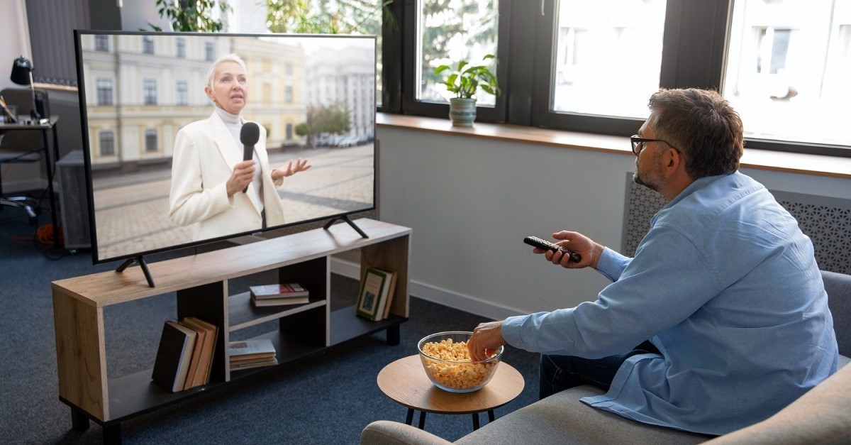 Un uomo guarda la TV sul divano