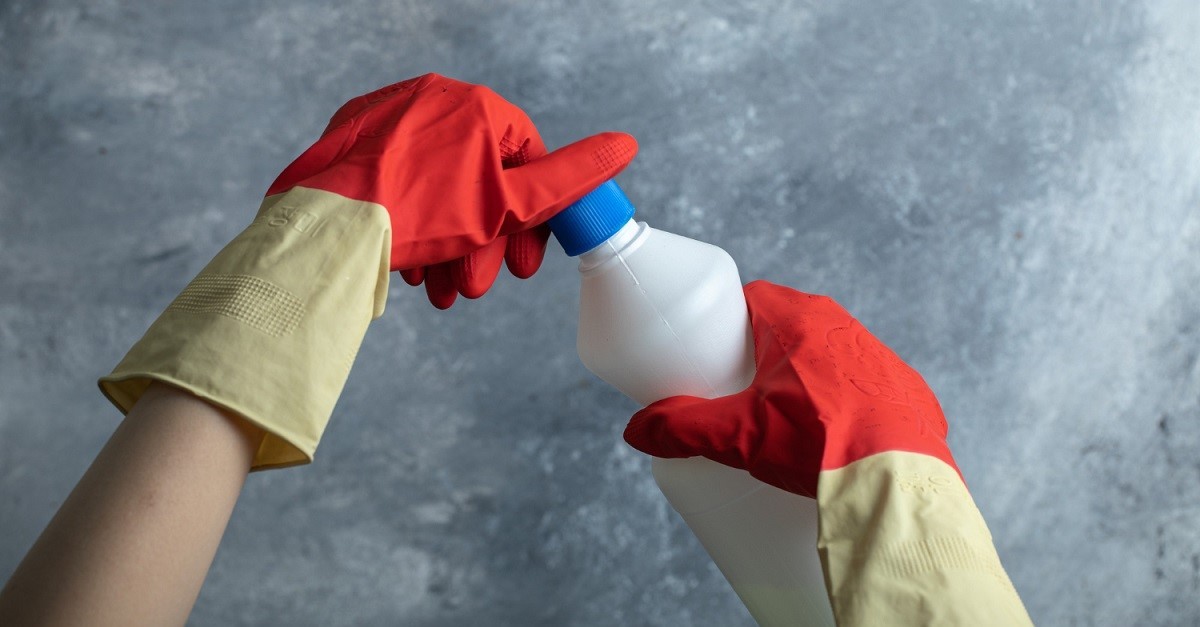 Flacone di candeggina maneggiato coi guanti