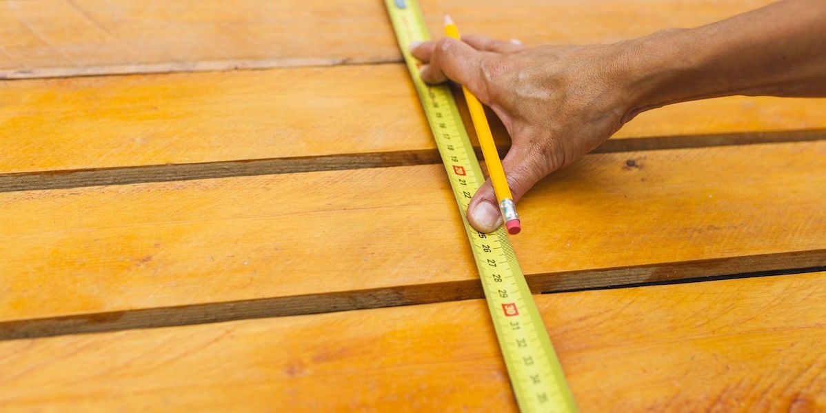 Mani di una persona che tiene un metro a nastro e misura la distanza in un cantiere edile in giardino