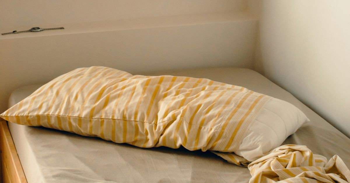letto ad angolo sotto a una finestra