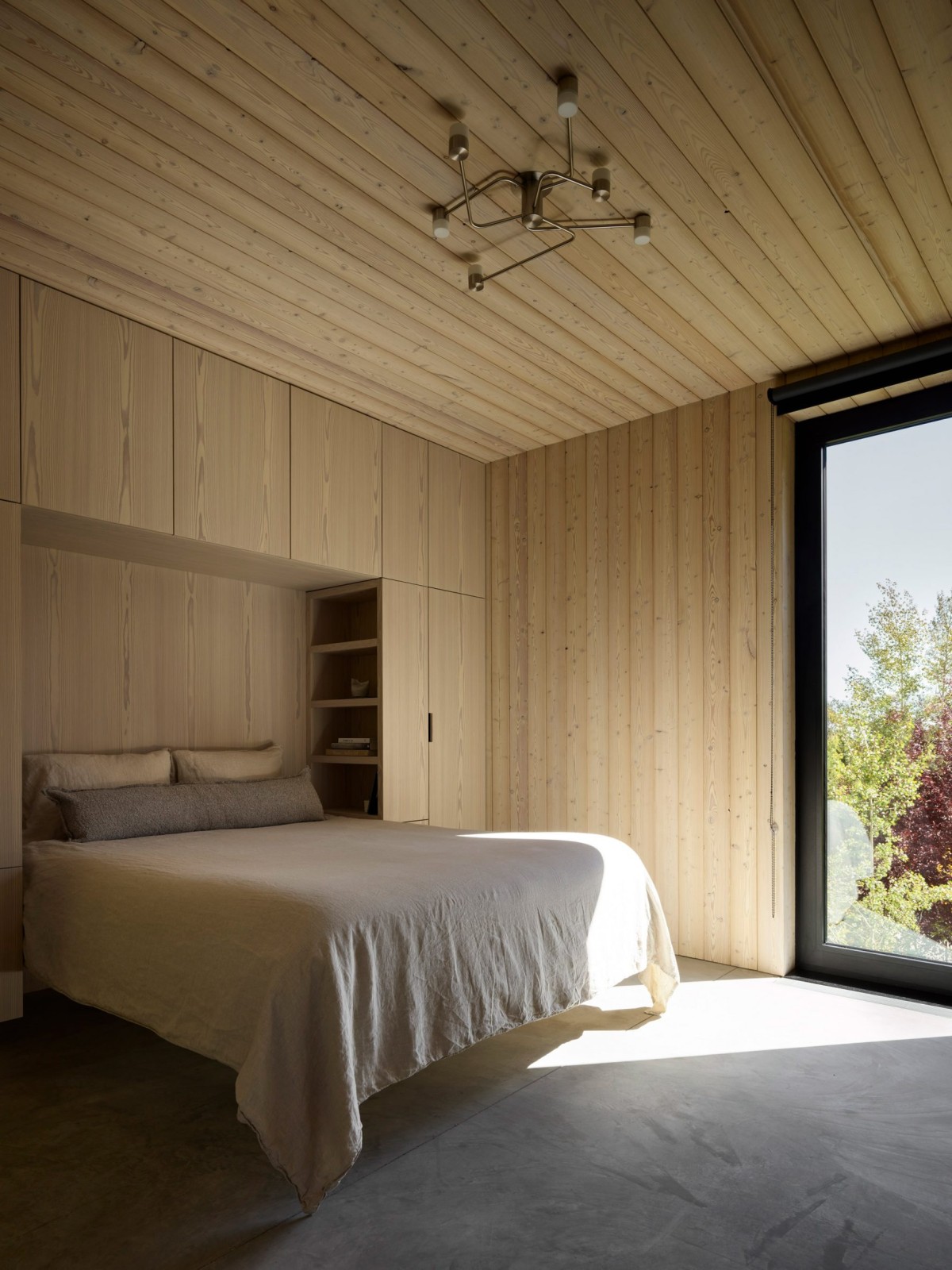 Nelle camere da letto, il legno di larice continua a rivestire pareti, soffitti e mobili a incasso