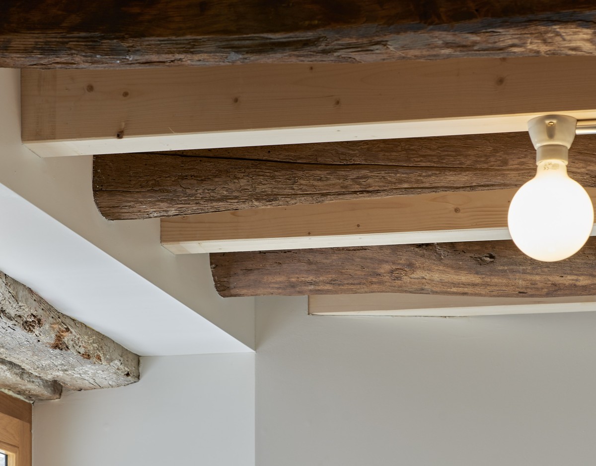 Travi di legno vecchie e nuove si alternano sul soffitto