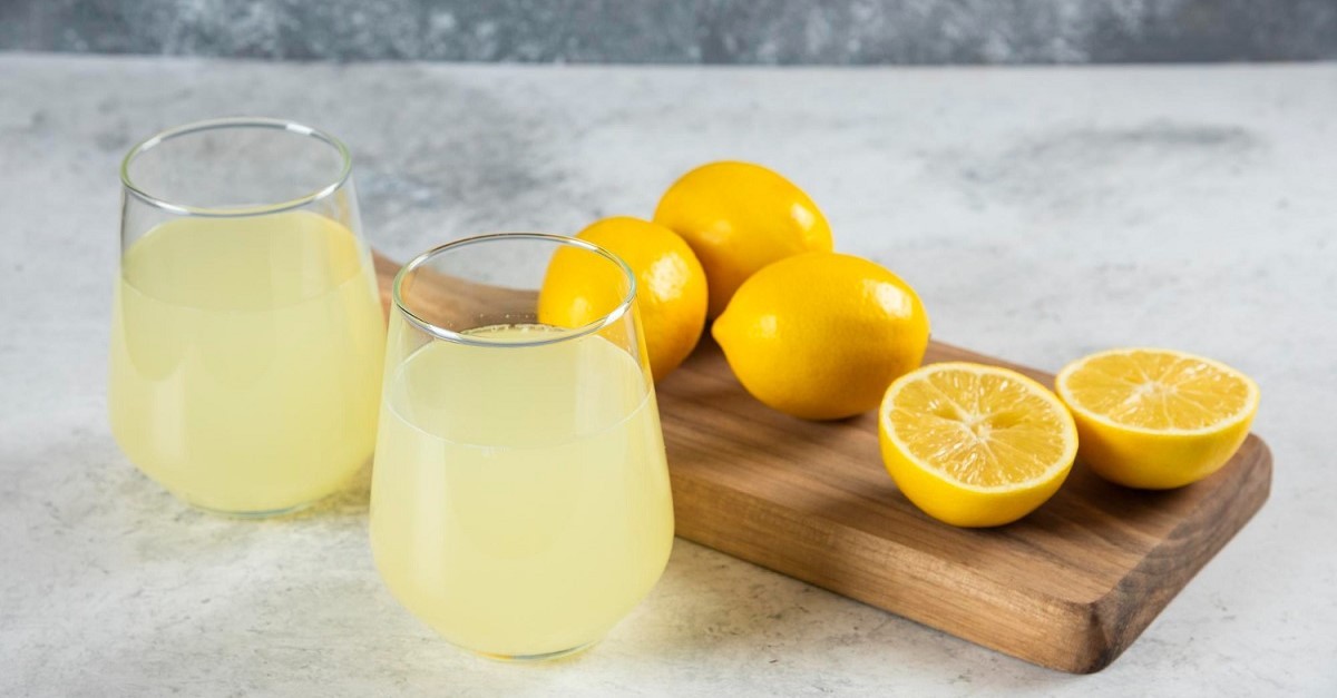 Succo di limone e limoni su un tagliere