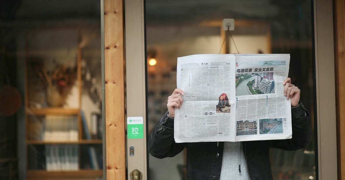Una persona legge un giornale davanti a una vetrina