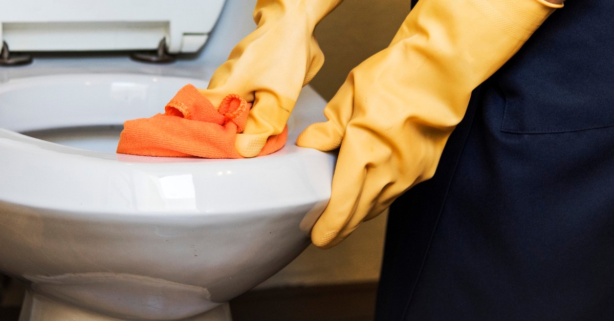 Pulire l'interno del water con un panno arancione e guanti gialli