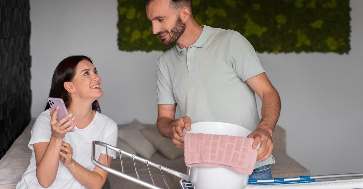 Coppia che stende la biancheria in casa