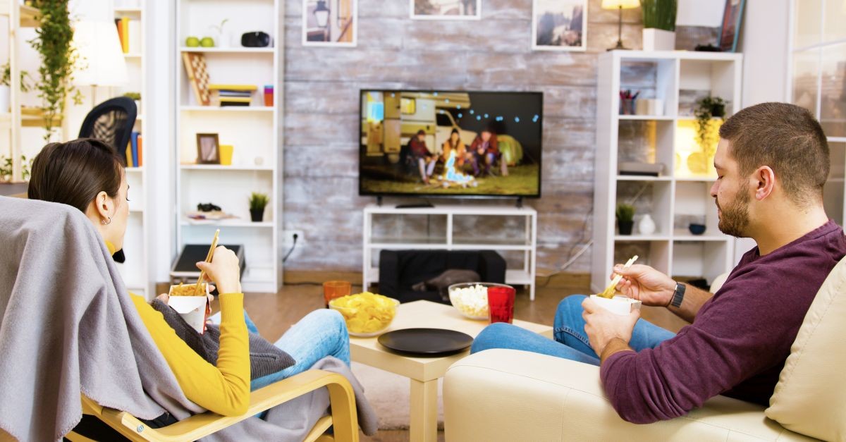 Giovane coppia che mangia davanti alla TV 