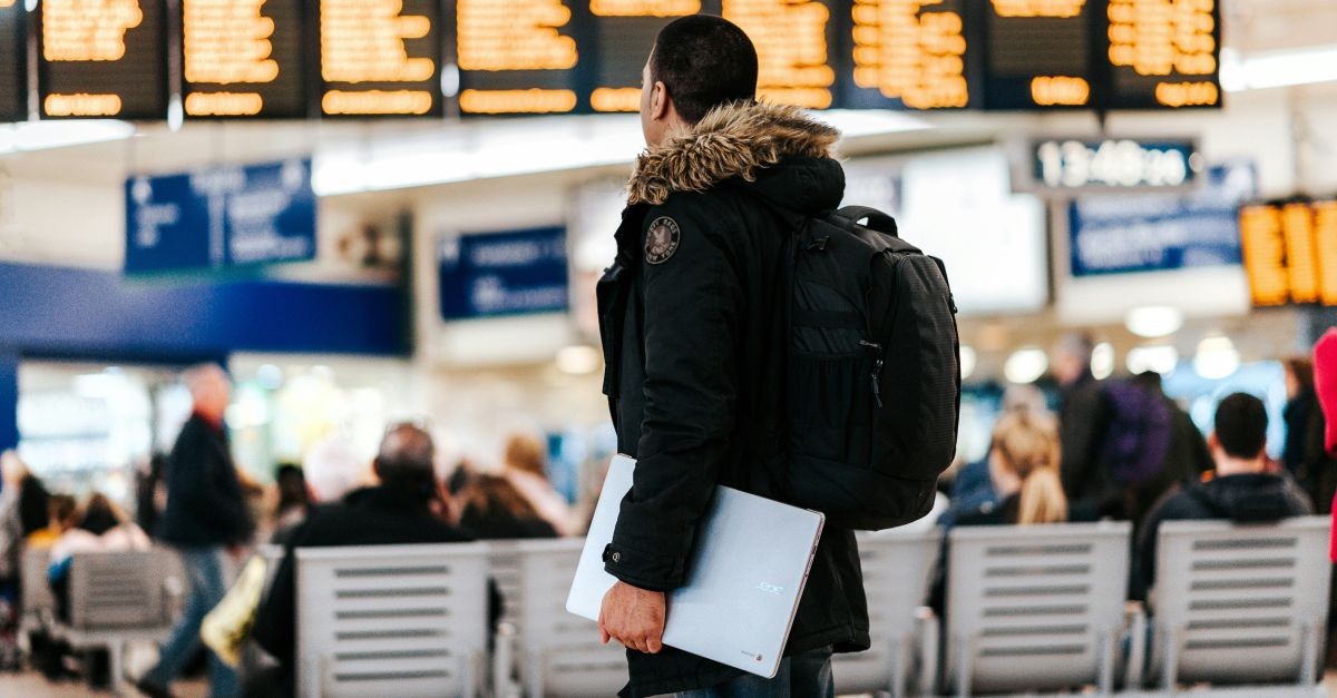 persona in aeroporto davanti ai tabelloni