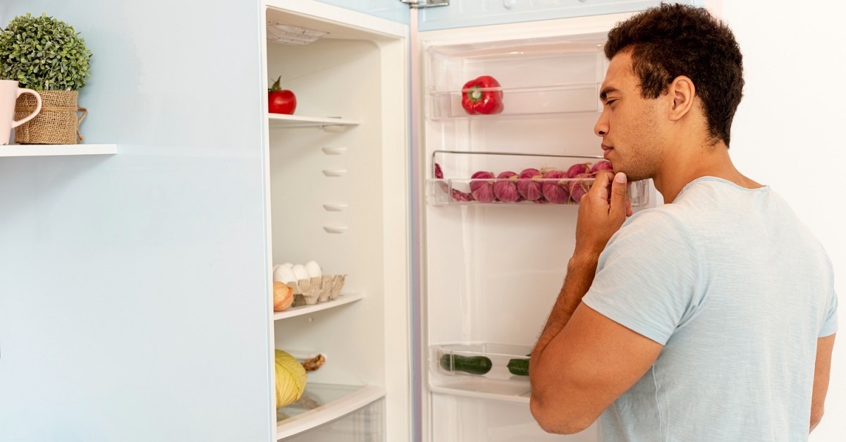 Uomo davanti a un frigo aperto