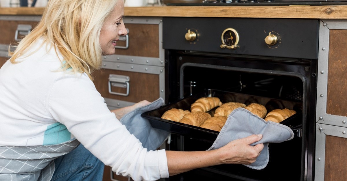 Donna estrae un vassoio di croissant dal forno
