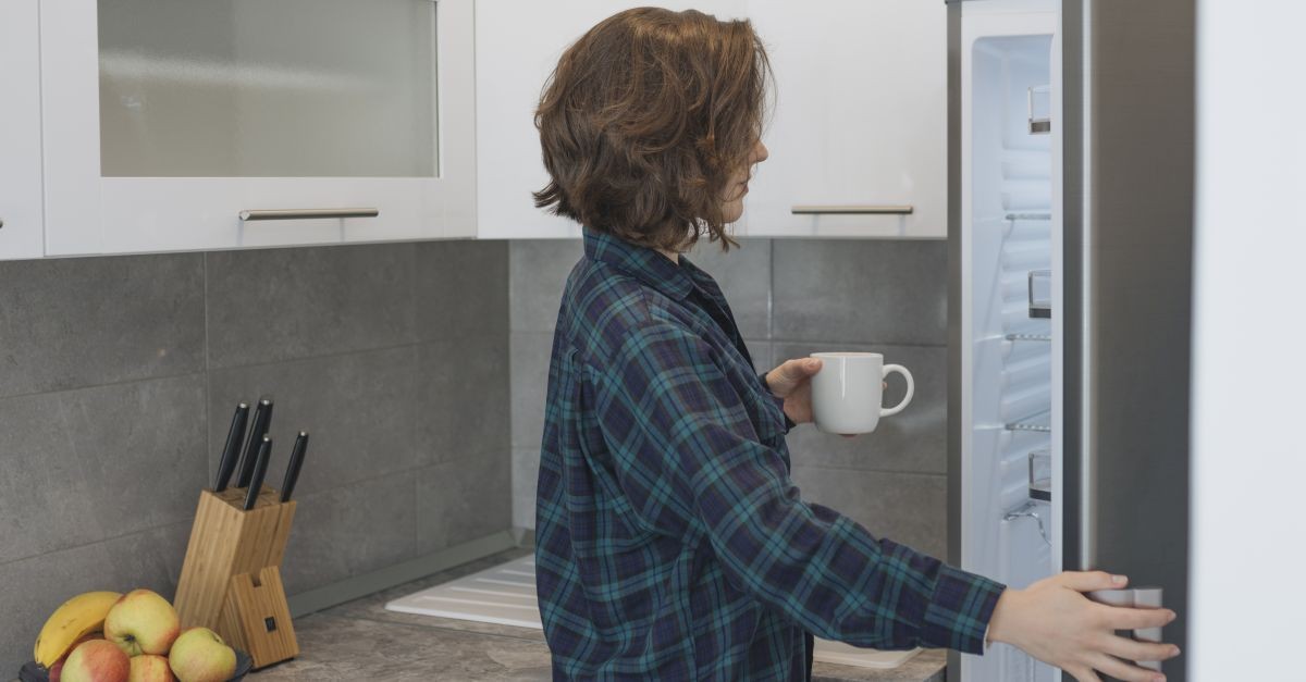 donna con tazza davanti al frigo 