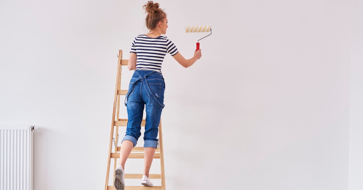 Ragazza sulla scala in legno dipinge la parete