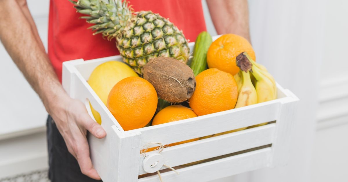 uomo che regge cassetta di frutta 