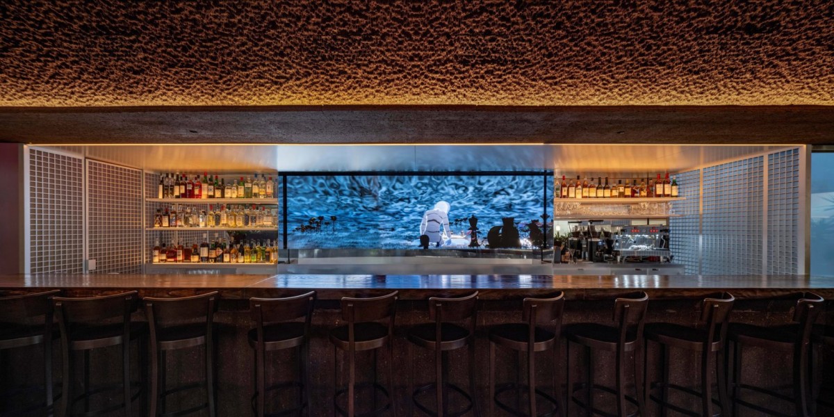 Sulla parete del bar, un'opera digitale e interattiva dell'autore Ian Cheng domina la scena visiva