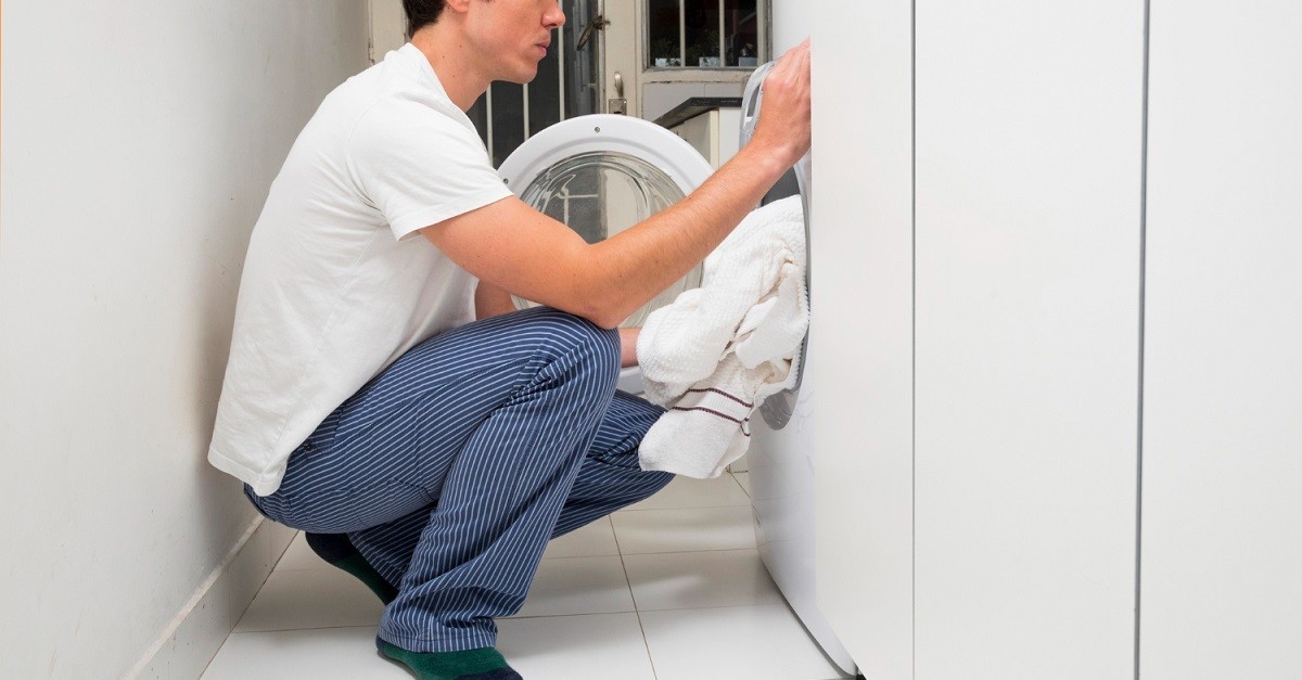 Uomo inserisce il bucato in lavatrice