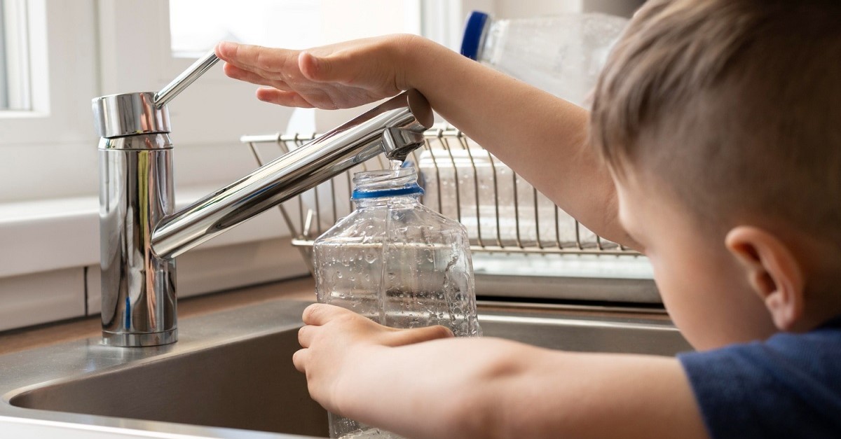 Un bambino raccoglie acqua dal rubinetto