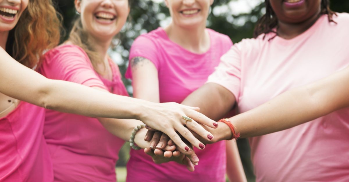 donne con magliette rosa uniscono mani 