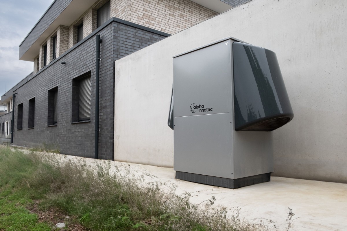 Sistema innovativo di pompa di calore di alpha innotec installato all'esterno di un edificio contemporaneo