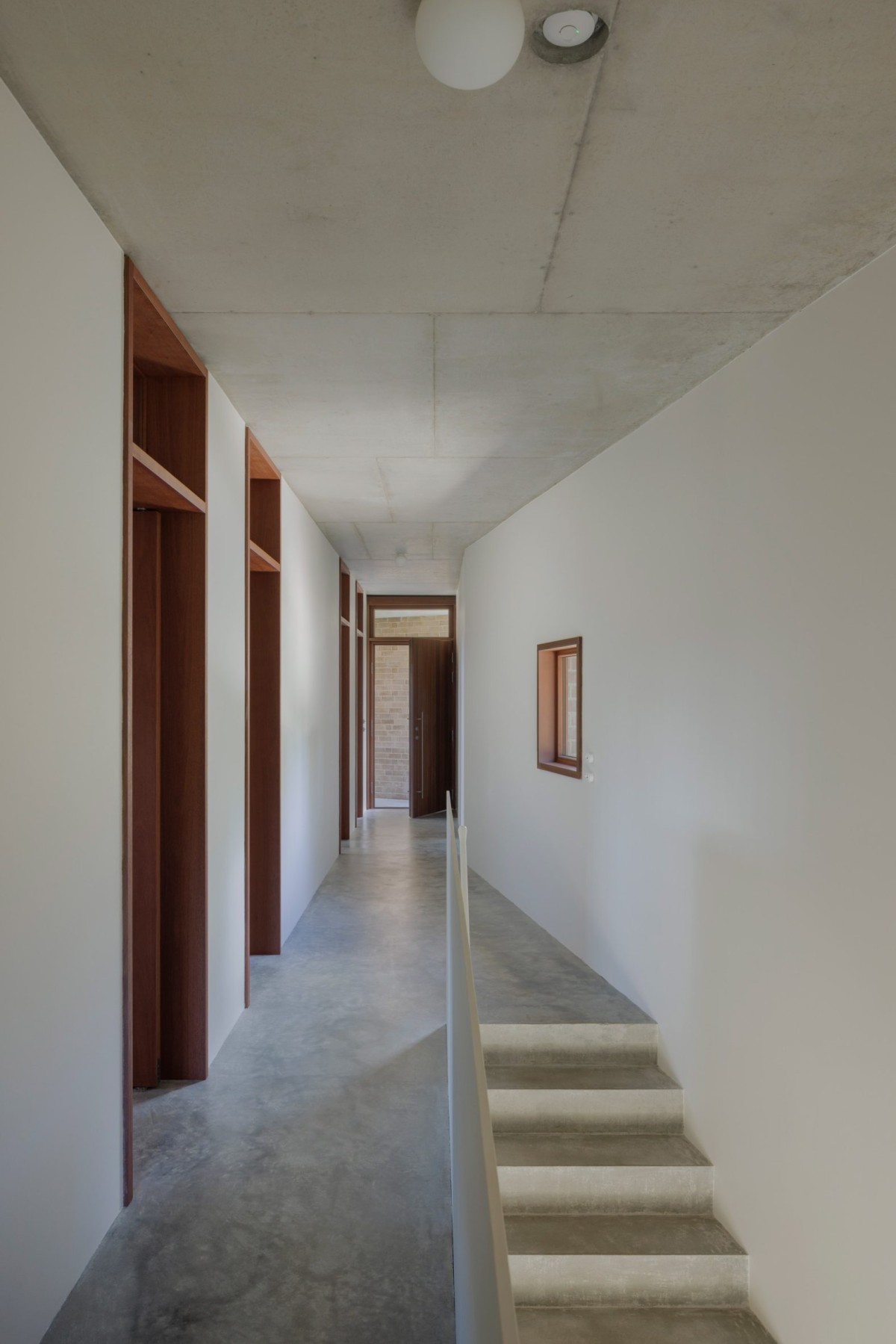El pasillo de distribución contrasta con el resto de la casa por su suelo de hormigón pulido.