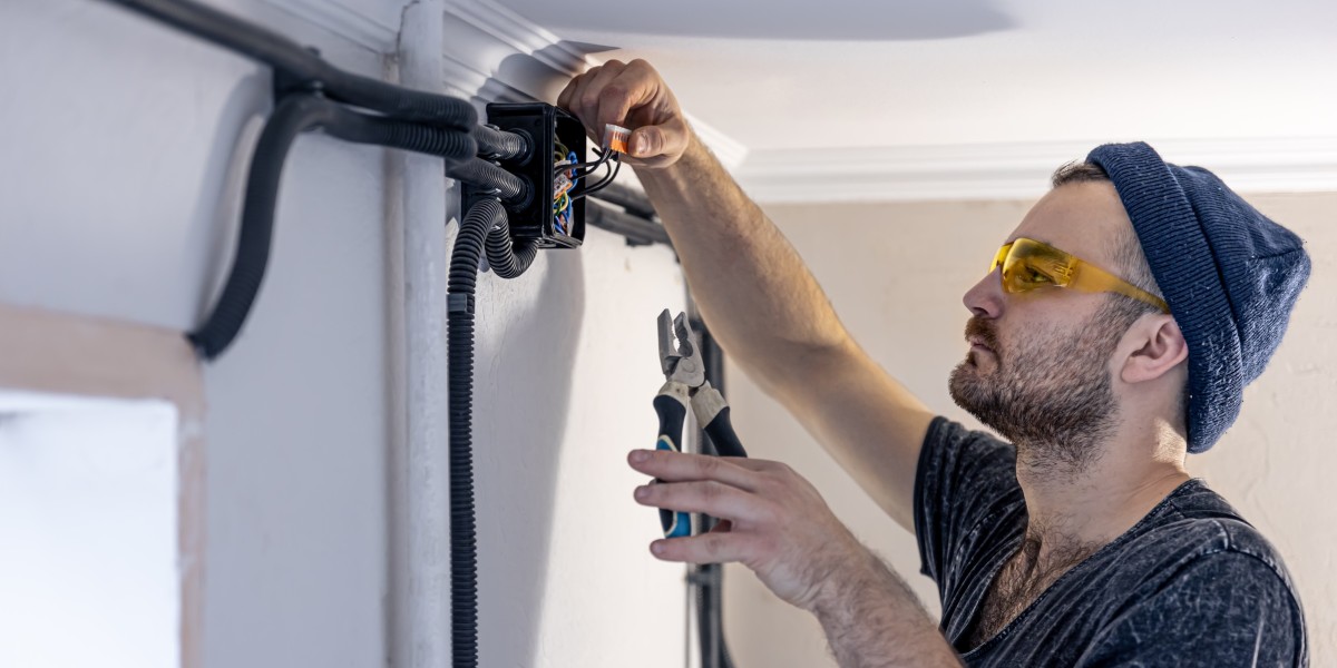 Elettricista installa prese elettriche su una parete bianca all'interno