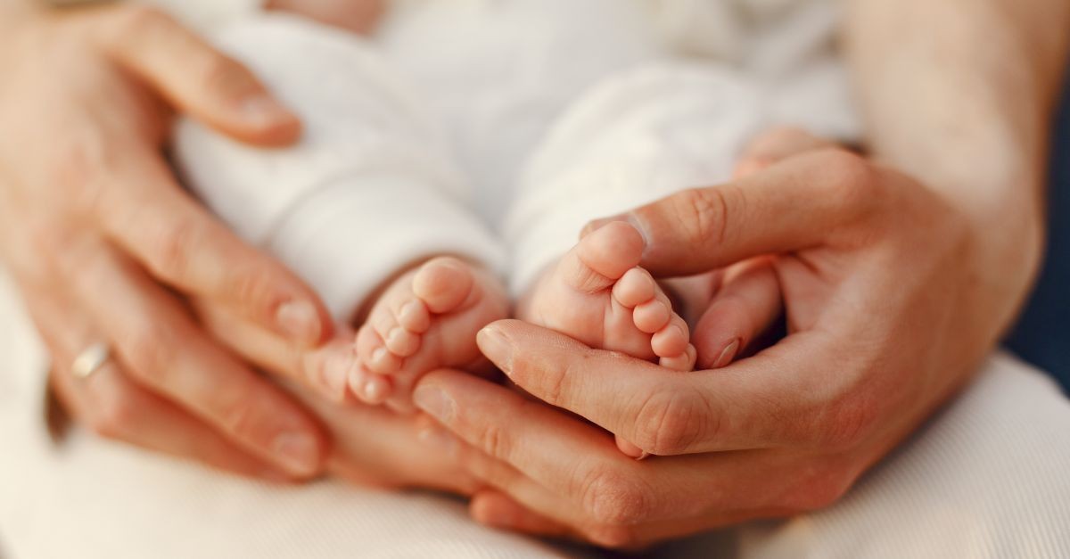 persona che afferra dolcemente i piedini di un bambino 