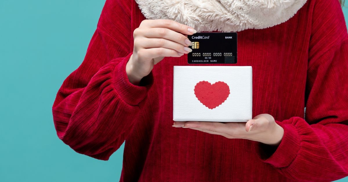 ragazza che mostra carta di credito appoggiata su un cuore 