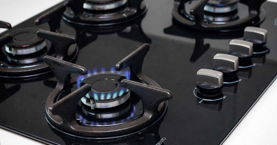 Una cucina a gas nera con un fuoco acceso