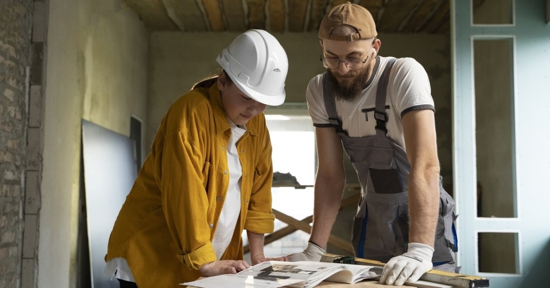 Un uomo e una donna con caschi di sicurezza che esaminano un progetto edile