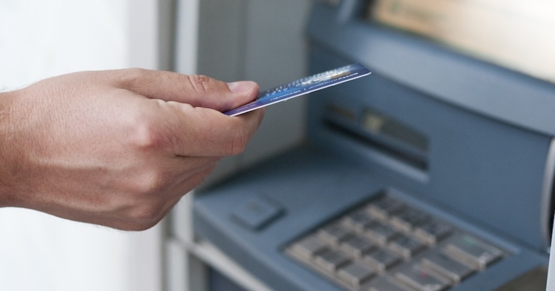 Mano che inserisce bancomat per prelevare