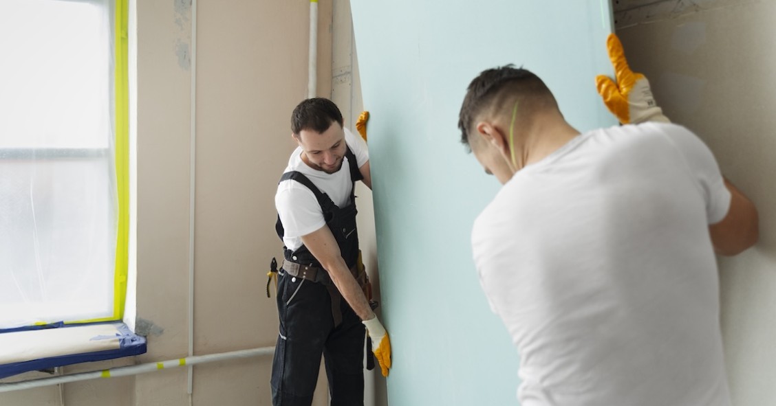 Cappotto acustico: che cos'è e quale scegliere tra esterno o interno Operai installano pannelli isolanti