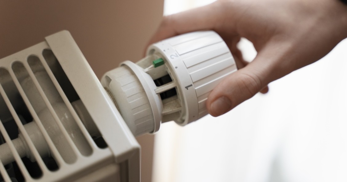 Primo piano di una mano che gira la manopola del riscaldamento