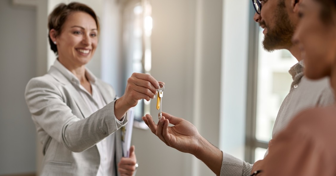 Agente immobiliare che consegna le chiavi della nuova casa a una coppia