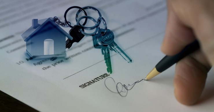 Firma di un contratto di diritto di abitazione con in primo piano le chiavi di casa